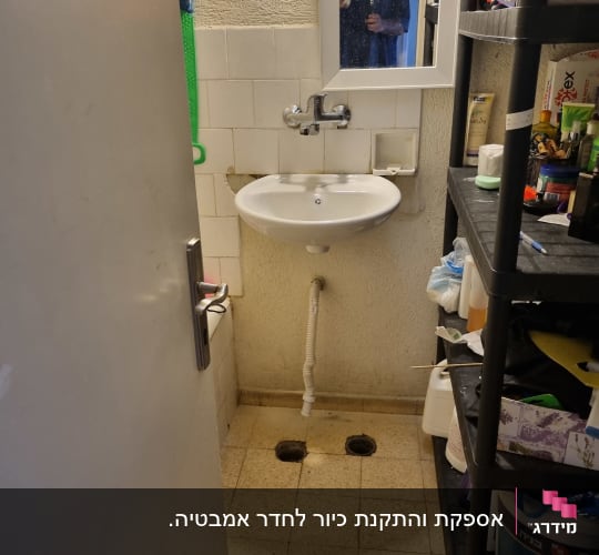 כיור עם ברז ומראה בחדר אמבטיה קטן